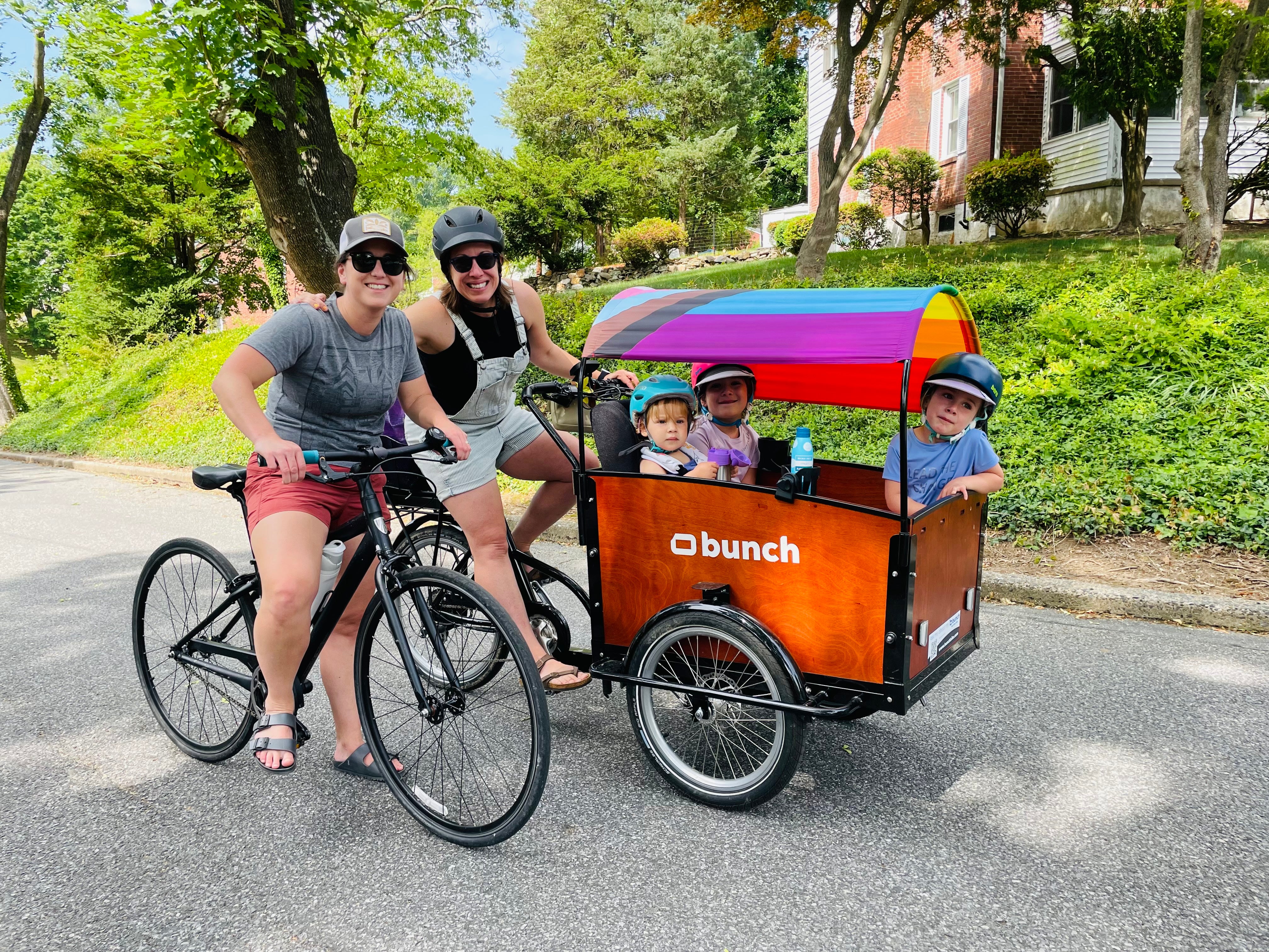 Two moms and three kids on bunch bike with pride flag in support of equality texas