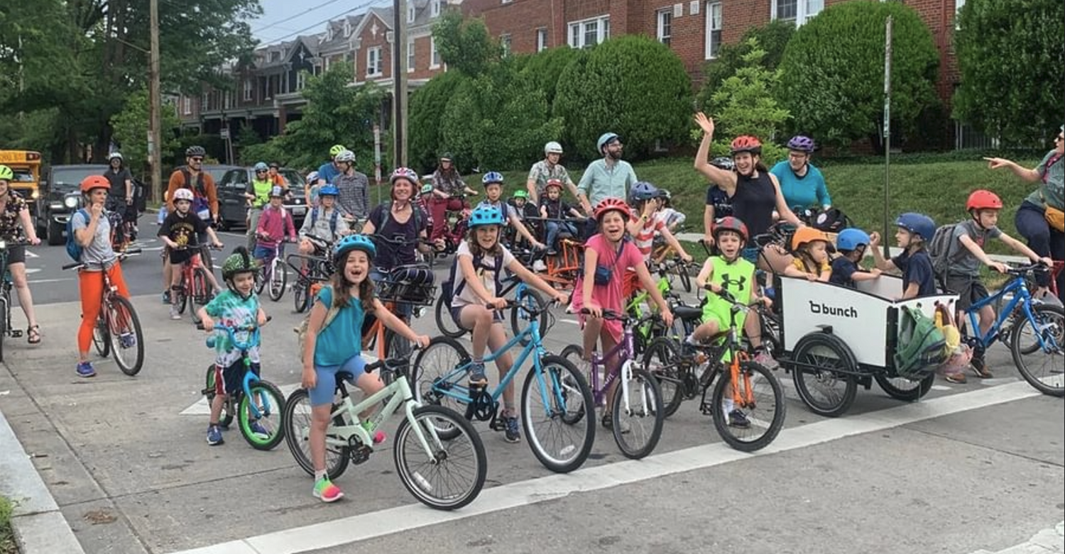 Bike bus with children on bikes led by white bunch bike