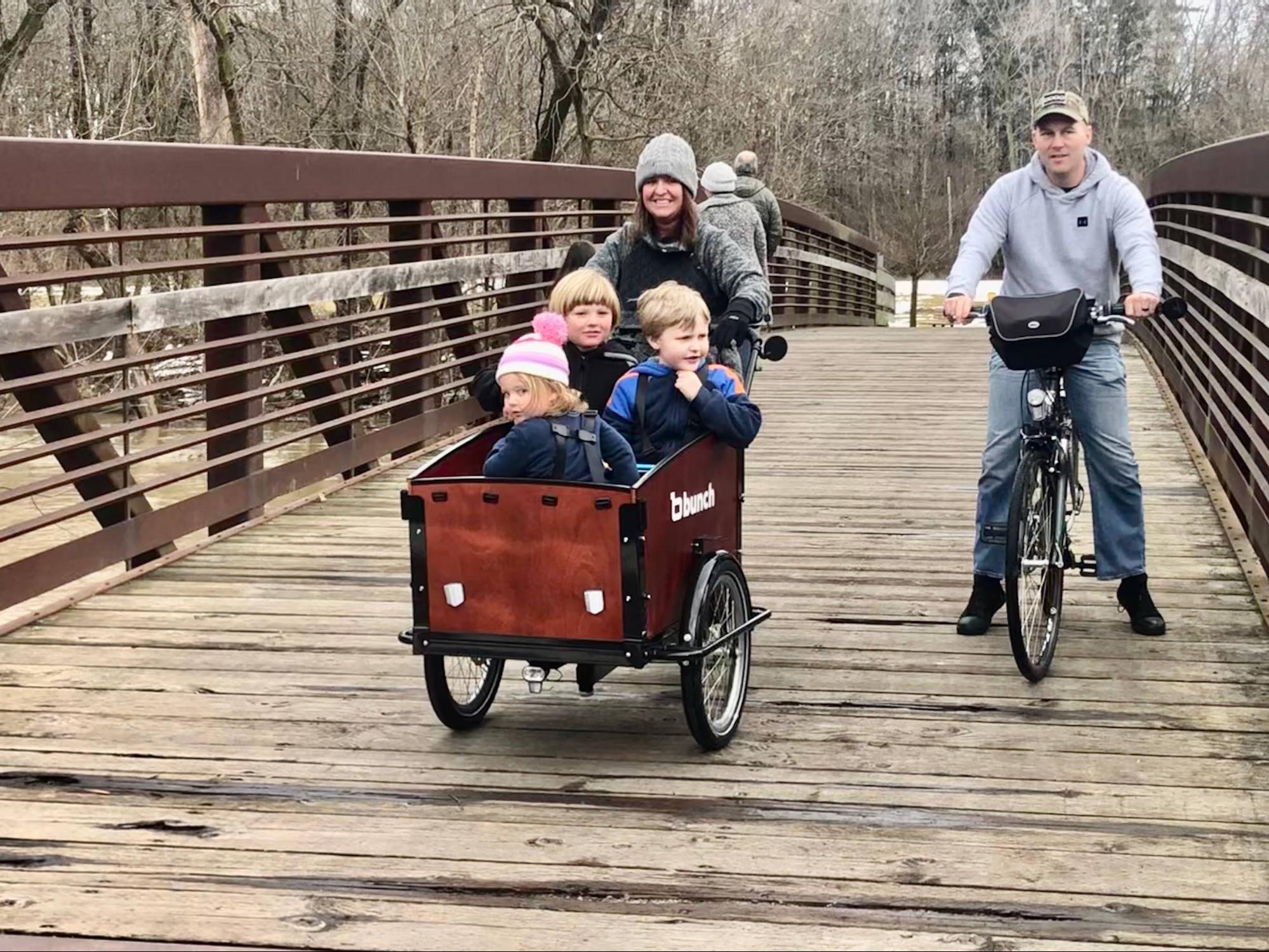 Dad on regular bike with mom and three kids on bunch bike