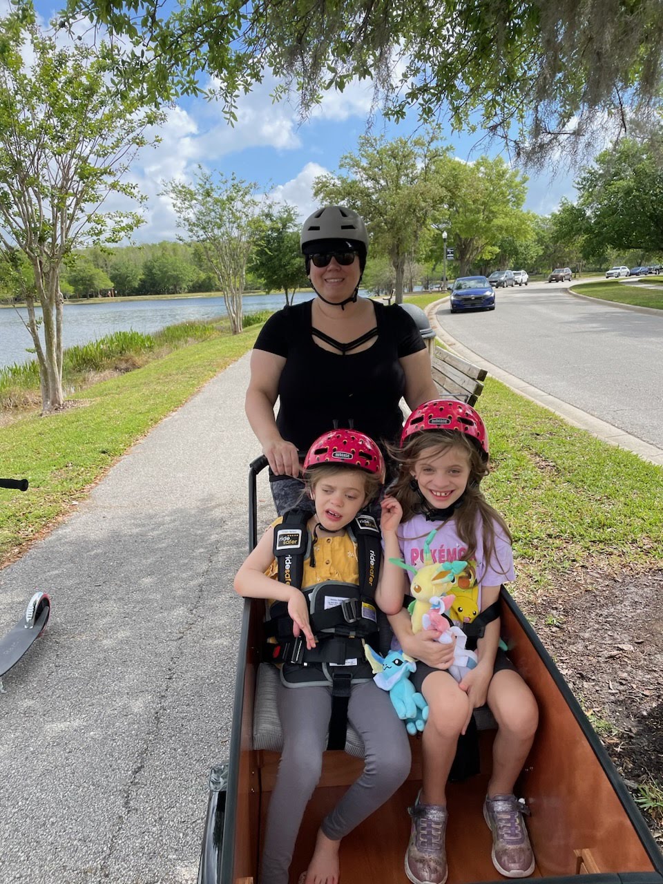 Twin girls in Bunch Bike, one in ride safer vest and one in standard seat belt
