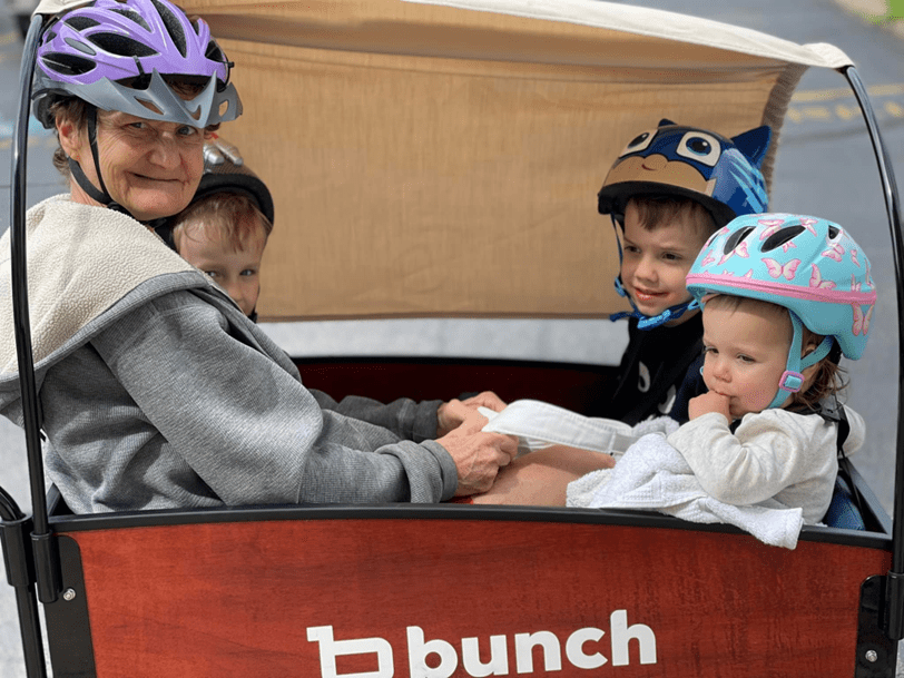 three children and an elder riding in the bunch bike together  #color_Sedona Woodgrain